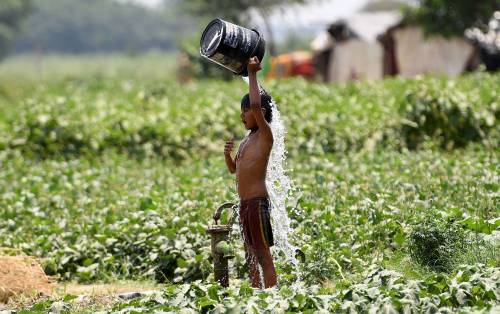 Un bambino versa l'acqua su se stesso per rinfrescarsi a New Delhi, India.